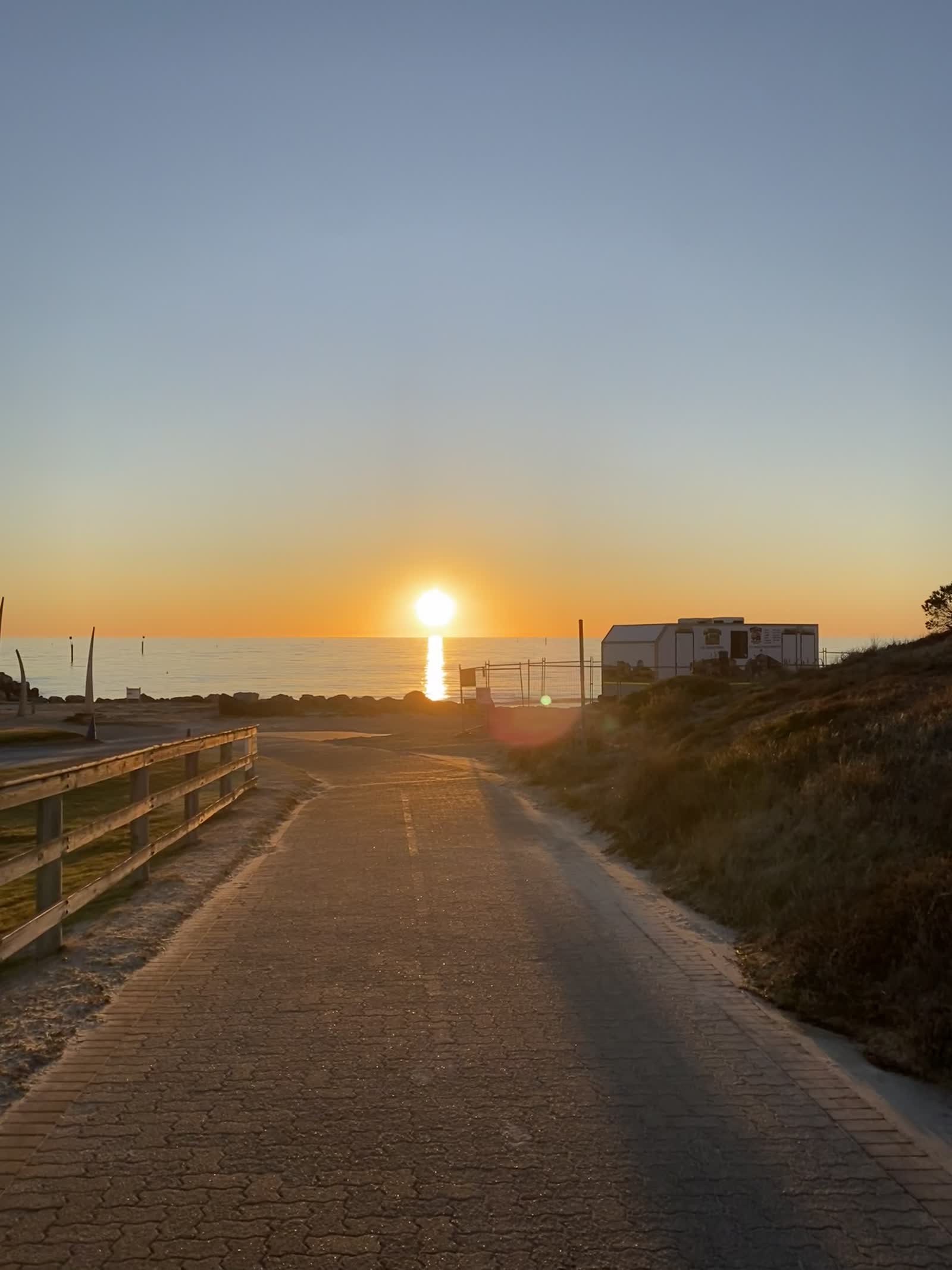 Pôr do sol sobre um caminho à beira-mar